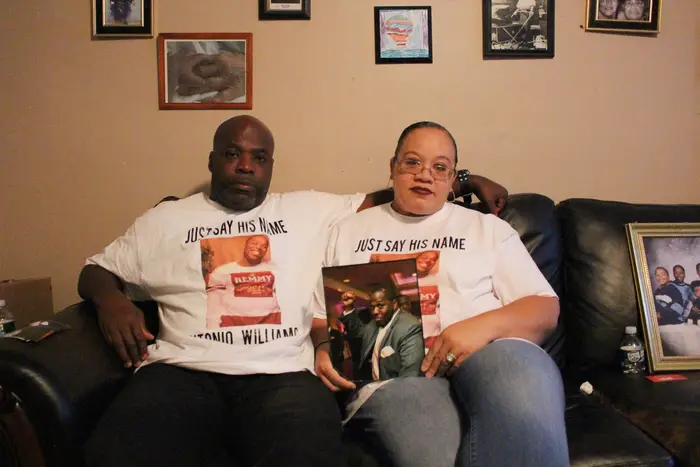 Shawn and Gladys Williams sit on a couch with a photograph of Antonio Williams on their lap.